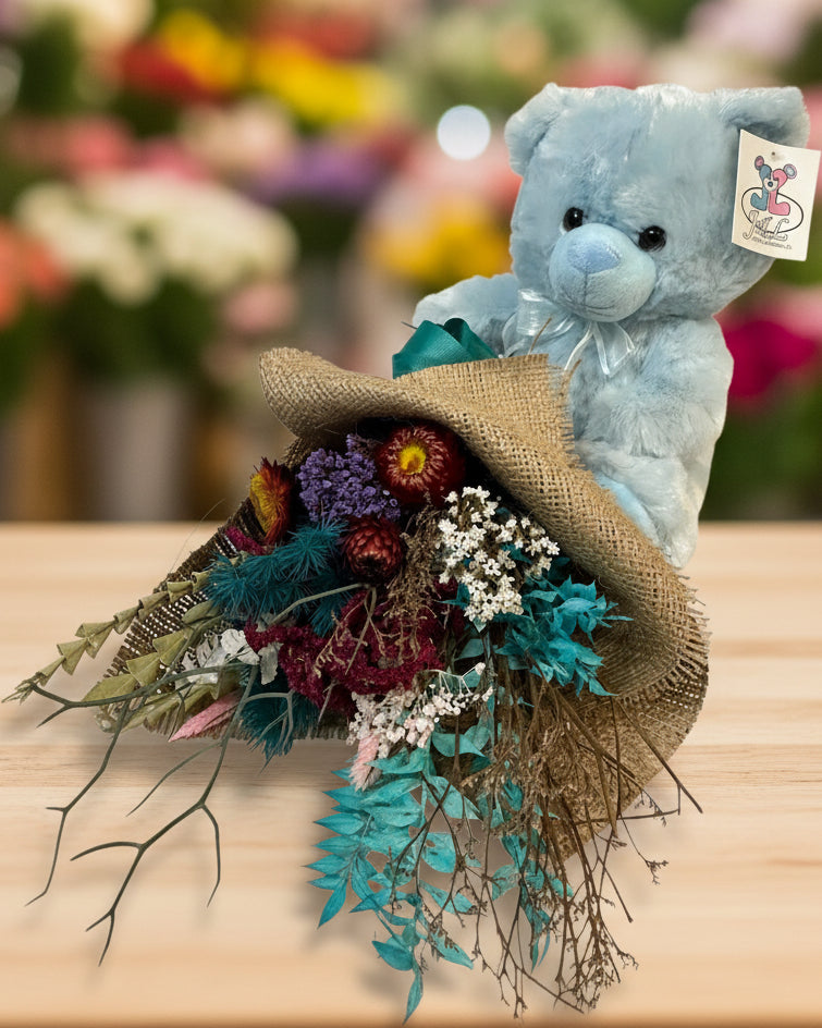 Blue teddy bear with a bouquet of flowers on a white background