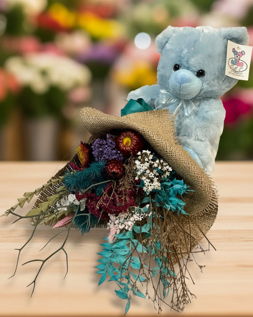Blue teddy bear with a bouquet of flowers on a white background