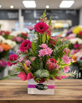 Floral arrangement with pink and green flowers in a box on a white background