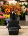 Black vase with dried flowers and a tag on a white background