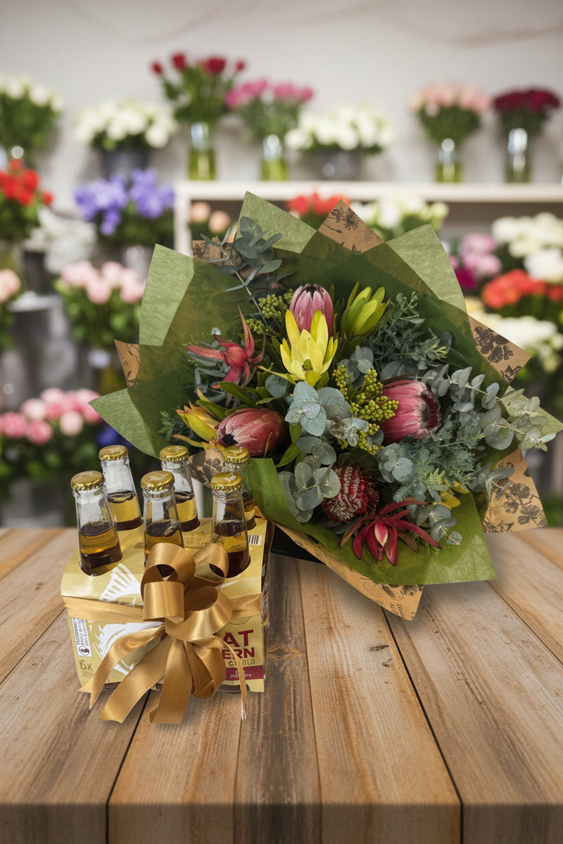 Bouquet of flowers with a box of beer bottles wrapped in gold ribbon on a white background