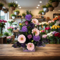 Floral arrangement with pink and purple flowers in a box on a white background