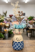 Decorative figure with floral headpiece and mermaid tail on a white background
