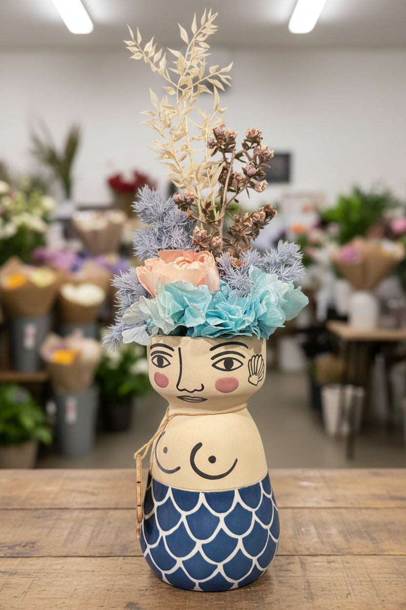 Decorative figure with floral headpiece and mermaid tail on a white background