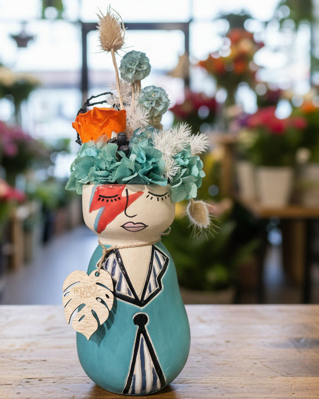 Decorative vase shaped like a face with floral elements on a white background