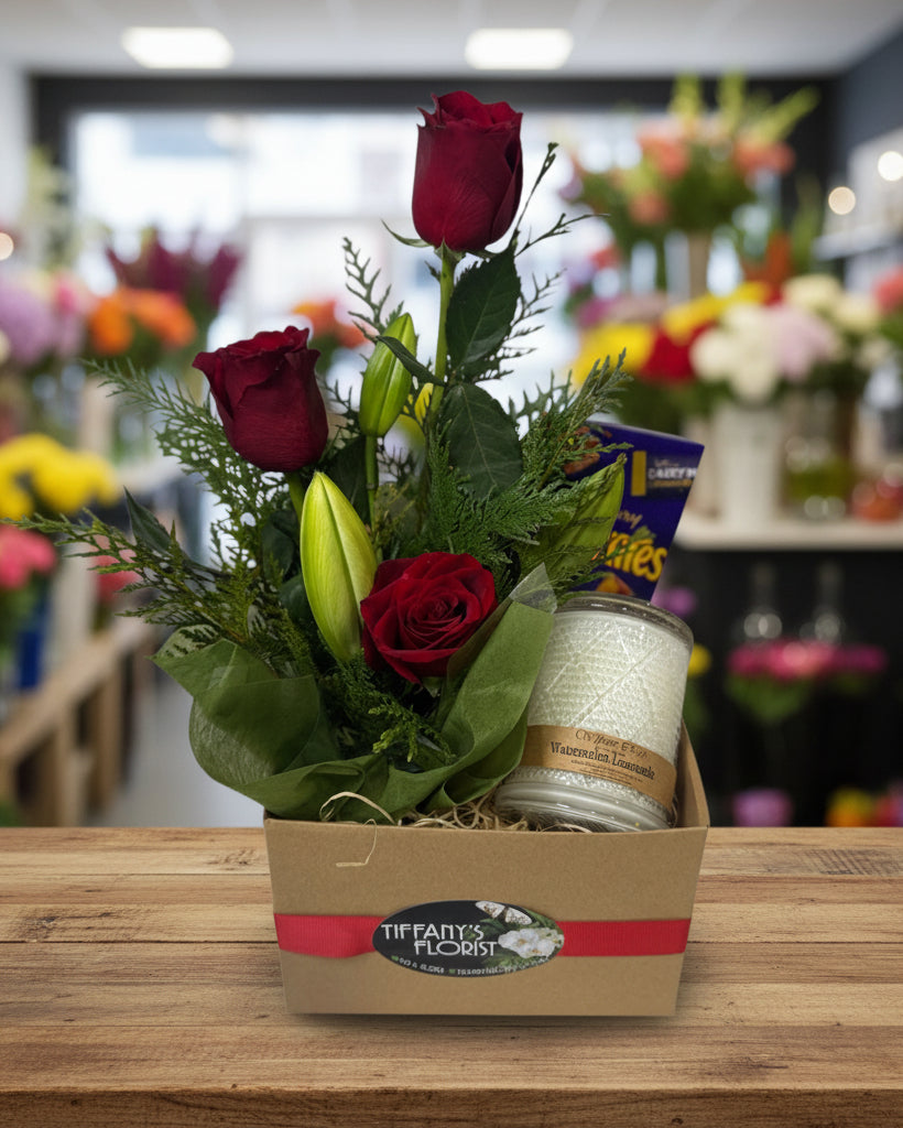 Floral arrangement with red roses and greenery in a box, featuring Tiffany's Florist branding.