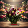 Bouquet of colorful roses with green leaves in a box on a white background