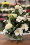 Bouquet of white flowers with green leaves in a box on a white background