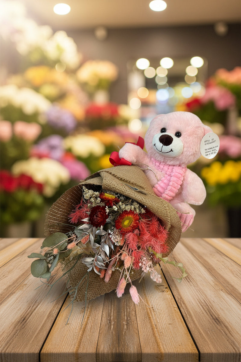 Pink teddy bear with a bouquet of flowers on a white background