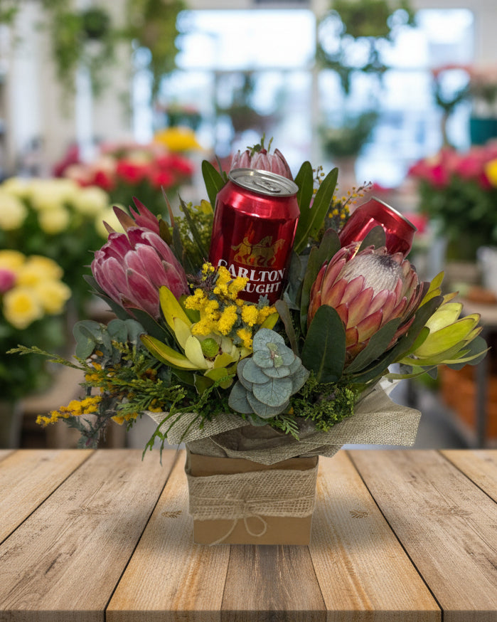 Floral arrangement with a can of Carlton Light beer surrounded by flowers on a white background