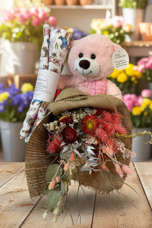 Pink teddy bear with a bouquet of flowers and a hat on a white background