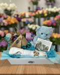 Gift basket with teddy bear, baby blanket, and other items on a white background