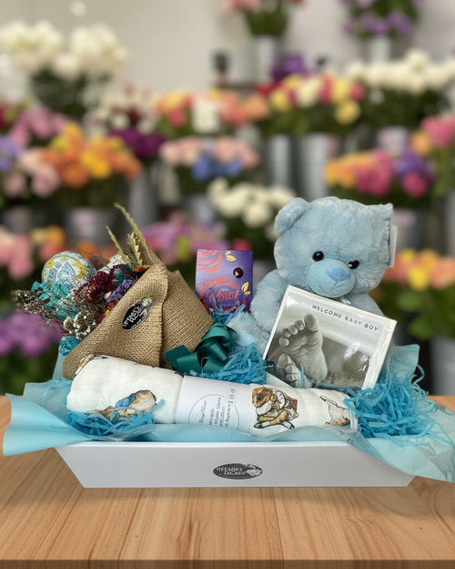 Gift basket with teddy bear, baby blanket, and other items on a white background